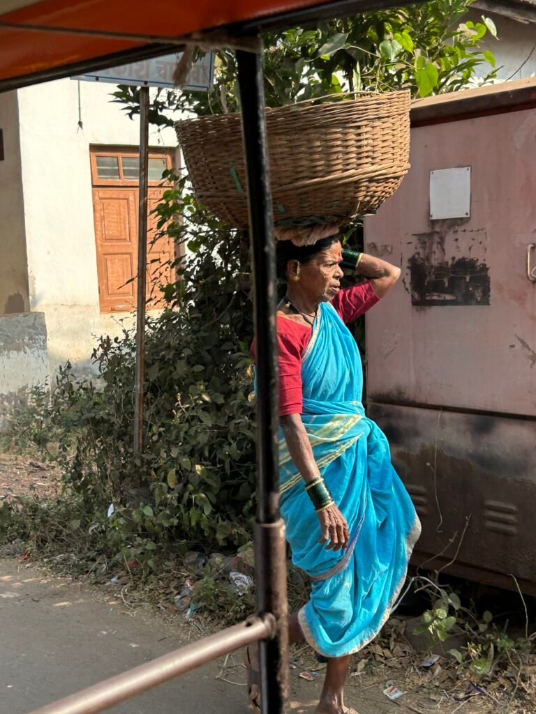 A glimpse of everyday life in a Konkan village as a woman carries a traditional basket through the street.