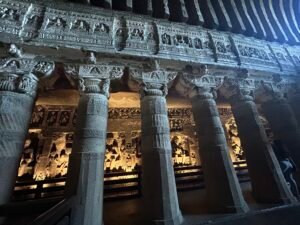 Intricately carved stone pillars and Buddhist sculptures inside Ajanta Caves in Maharashtra, India.